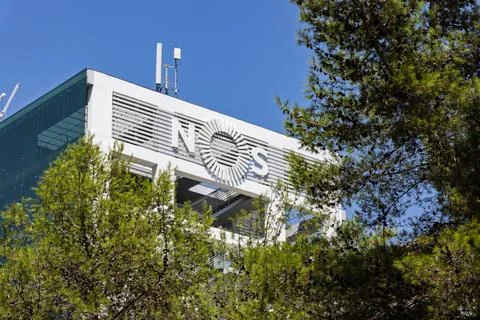 A view of the upper part of a white building with the NOS logo, partially obs Stock Photos