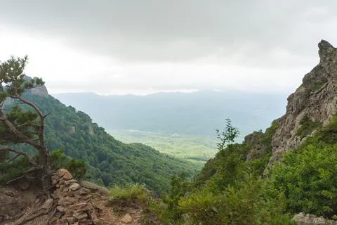 View of the valley from the height of the mountain range in a cloudy sky 库存照片