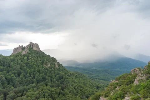 View of the valley from the height of the mountain range in a cloudy sky Stock Photos