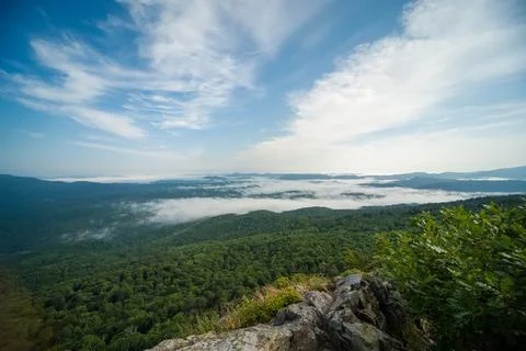 View of the valley from the height of the mountain range in fog 库存照片