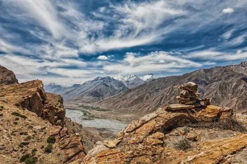 View of valley in Himalayas with stone cairn on cliff Stock Photos