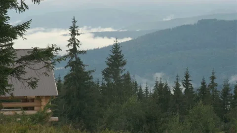 A view of the valley in mountains with low clouds. a wooden house in a foregroun Stock Footage 205608331