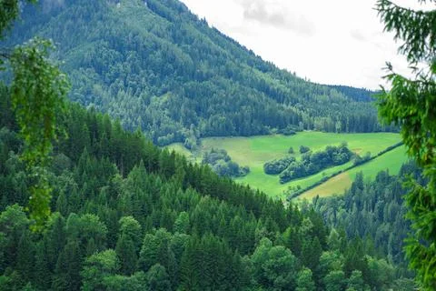 View of the valley from the top of the Alpine mountains against a cloudy sky Stock Photos