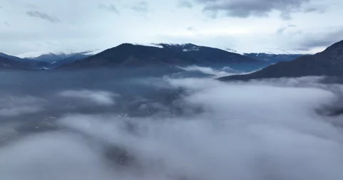 View of valley with trees, lake and city against backdrop of mountains and fog. Stock Footage 174392645