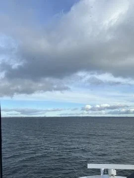 View of a vast ocean under a dramatic cloudy sky, with a hint of land on the Stock Photos