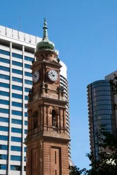 View of a Victorian style clock tower with modern buildings in background Stock Photos