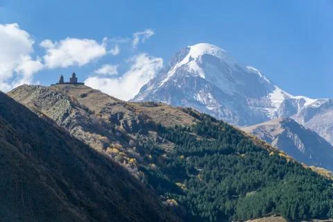 View of village Stepantsminda, Gergeti Trinity Church and mount Kazbek in Sunny Stock Photos
