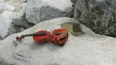 View of violin lying on large stone somewhere in mountains. Music everywhere. Stock Footage 142286802
