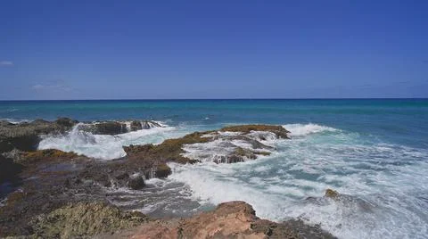 View of the volcanic cliffs on the tropical beach of Oahu Hawaii. Waves crash Stock Photos