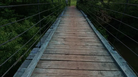 View of walking across an old, rustic wooden suspension bridge 库存影片 340067000