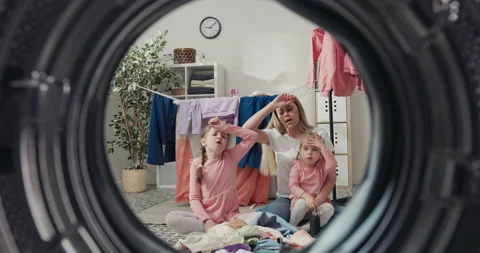 View from the washing machine drum to laundry rooms. A mother and two daughters Stock Footage 199893315