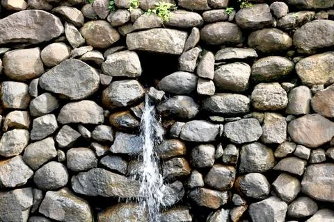 View of water falling from small stone wall Stock Photos