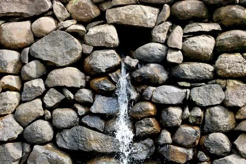 View of water falling from small stone wall Stock Photos