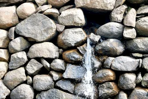 View of water falling from small stone wall Stock Photos