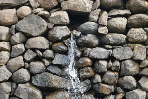 View of water falling from small stone wall Stock Photos