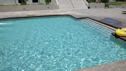 View of water slides ending in crystal clear swimming pool with inflatable tube Stock Footage 340072481