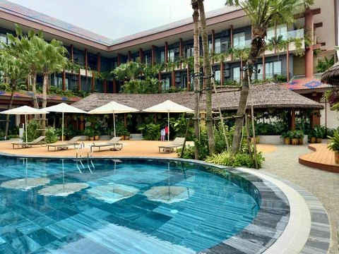 View from water surface towards sun loungers and thatched roof area Stock Photos