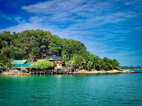 View of a waterfront house surrounded by trees and blue water on a sunny da.. Stock Photos