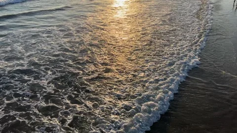 View of waves rushing in on the sand from above at sunset Stock Footage 247409581