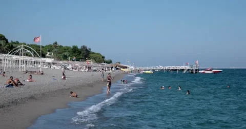 View of Waves at Sea Coast Line With People and Boats Moored to Pier at Summer Stock Footage 68686966