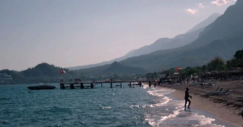 View of Waves at Sea Coast Line With People and Boats Moored to Pier at Summer Stock Footage 68686991