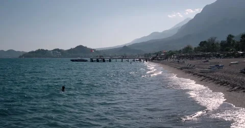 View of Waves at Sea Coast Line With People and Boats Moored to Pier at Summer Stock Footage 68686996