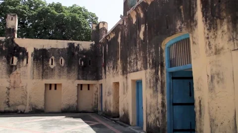 A view of the weathered, cream-colored stone walls and blue doors within the 스톡 동영상 345028968