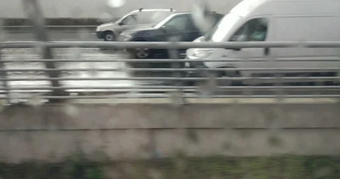 View from the wet window of a speeding train to a road with city traffic Stock Footage 111837604