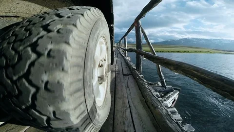 View of the wheel of the car passing over the bridge. Auto travel: SUV rides on Stock Footage 110327179