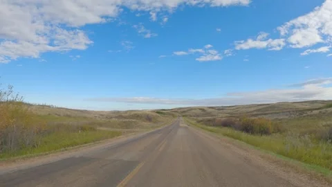 View while driving an old paved road through hilly open ranch land with blue sky Stock Footage 287106542