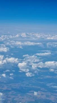 View of the white clouds and Earth from the airplane porthole. Travel concept Stock Photos