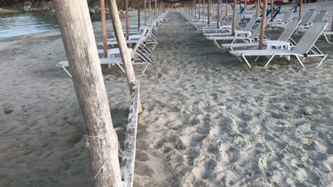 View on white vacant sunbeds under straw sun umbrellas due to Covid-19 Stock Footage 134665095