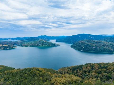 View of a wide river surrounded by hills and trees on a cloudy day in a rur.. Stock-Fotos