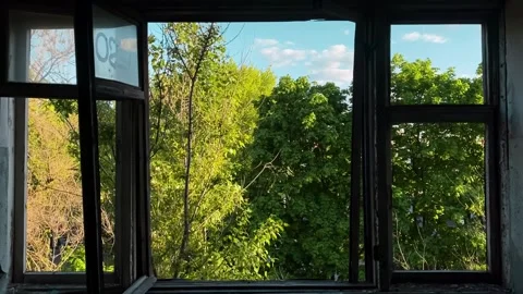 View from the window of an abandoned building to a clear sky and green trees Video stock 261761691