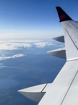 View from the window of an airplane flying above the clouds and sky. Stock Photos