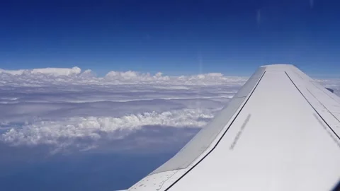 View from the window of an airplane on its wing and white clouds under the blue Stock Footage 255214074