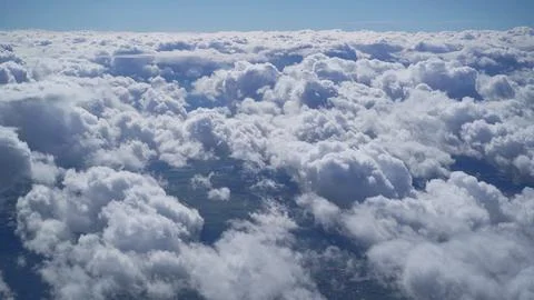 View from the window of an airplane on white fluffy clouds over the city Stock Photos