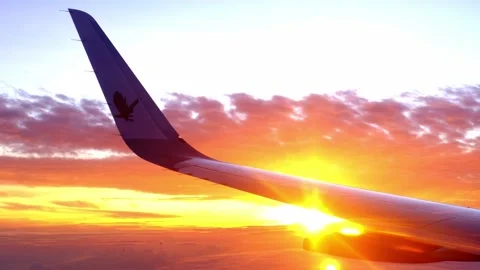 View from window on airplane wing plane while flying above dawn clouds, sun.. Stock Footage 229654053