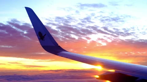 View from window on airplane wing plane while flying above dawn clouds, sun.. Stock Footage 235704363