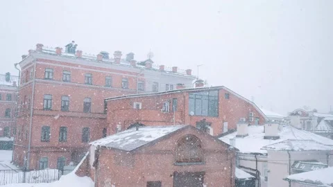 View from the window on brick buildings. The snow is falling in large flakes. Vídeos de archivo 176450008