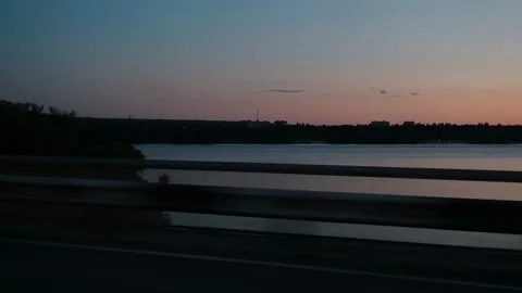 View from the window of the car on the river during sunset. The car drives over Stock Footage 220325159