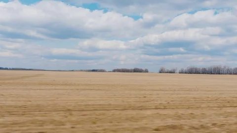 View from the window of a fast-moving car. Field early spring - plowed land and Stock Footage 74379693