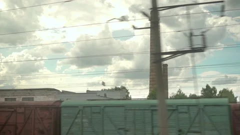 View from window of high-speed train on landscape of old rusty boxcars and high Video stock 156306878