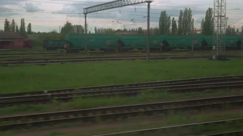View from window of high-speed train on landscape of old rusty boxcars and high Video stock 157372384