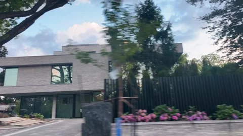 A view from a window of a moving car on a public road shows a brick mansion. Stock Footage 343675967