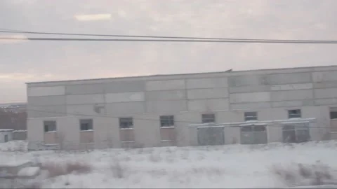 View from the window of a moving train at dawn passing by a winter town with Stock Footage 195104126
