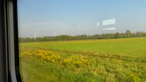 View from the window of a moving train on a sunny summer day, showcasing fields Stock Footage 285073914