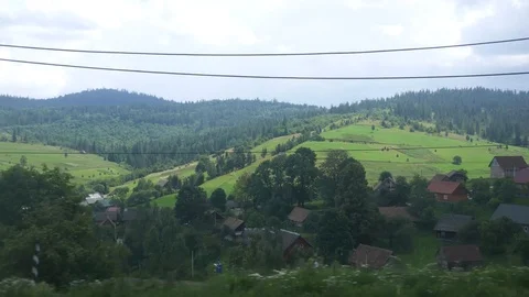 View from the window of a moving train to a village in the Carpathian Mountains. Stock Footage 93276247