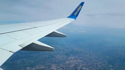 View from the window of the plane on the clouds and the ground, flying above the Stock Footage 99759593