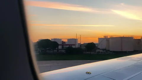 View from window of plane on fuel storage silos. Airplane on runway at sunset Stock Footage 265128260